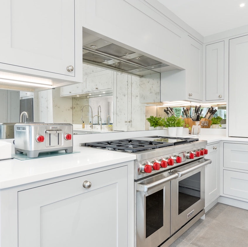 Rough Old Glass Antiqued Mirror Splashback with Wolf Range Cooker. Kitchen Design by Maple & Gray